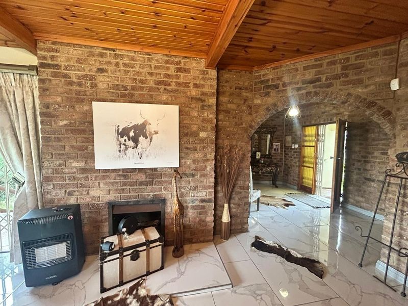 Living room featuring exposed brick walls, a timber ceiling, and tiled flooring with an arched transition to the entryway.