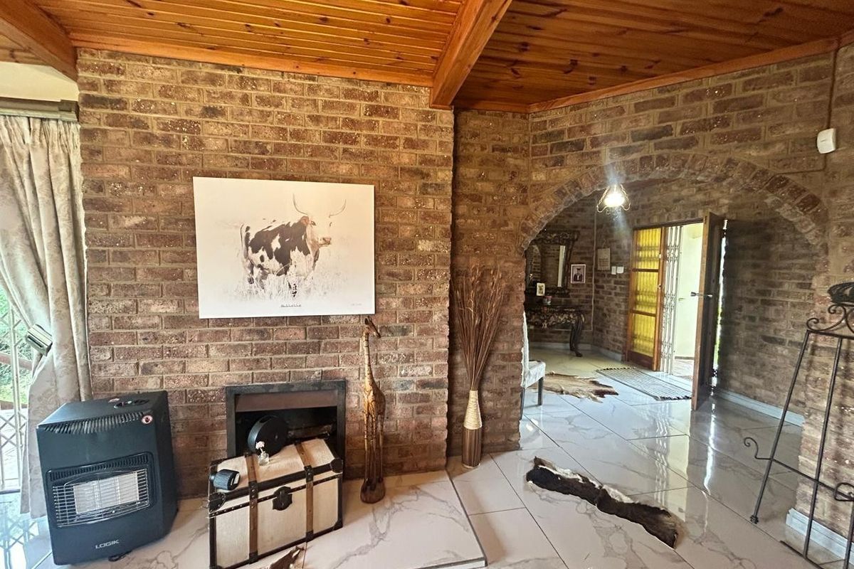 Living room featuring exposed brick walls, a timber ceiling, and tiled flooring with an arched transition to the entryway.