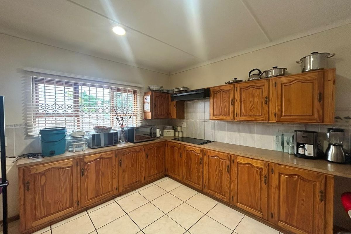 A functional kitchen featuring traditional wooden cabinetry, laminate countertops, tiled backsplash, and ceramic flooring, offering a classic layout with ample storage space.