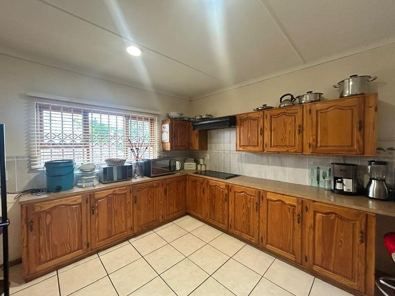 A functional kitchen featuring traditional wooden cabinetry, laminate countertops, tiled backsplash, and ceramic flooring, offering a classic layout with ample storage space.