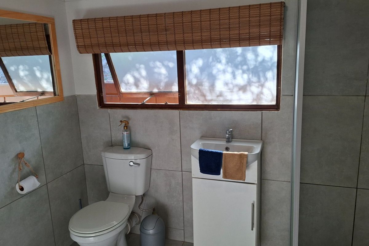 A functional bathroom featuring tiled walls, a vanity basin, and a toilet, with natural light provided by a window.