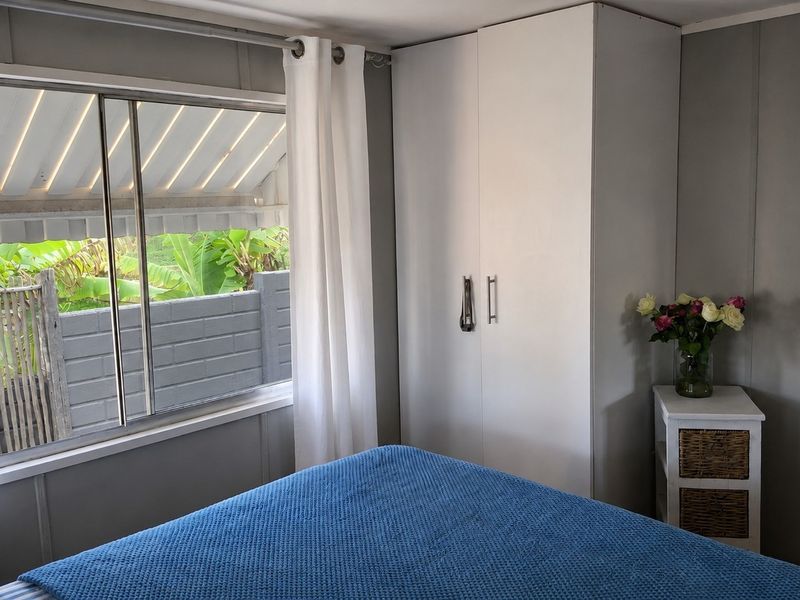 A functional bedroom featuring a built-in wardrobe, sliding window with an external awning, and neutral wall finishes.