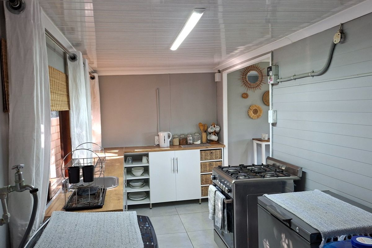 Compact kitchen featuring built-in cabinetry, a gas stove, stainless steel sink, and tiled flooring with functional layout.