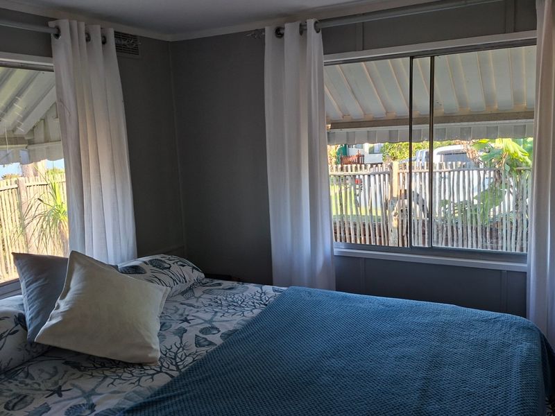 A bedroom featuring dual sliding windows with curtain tracks, providing natural light and views of the exterior area.