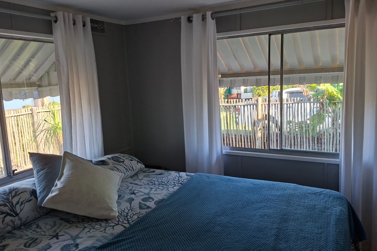 A bedroom featuring dual sliding windows with curtain tracks, providing natural light and views of the exterior area.