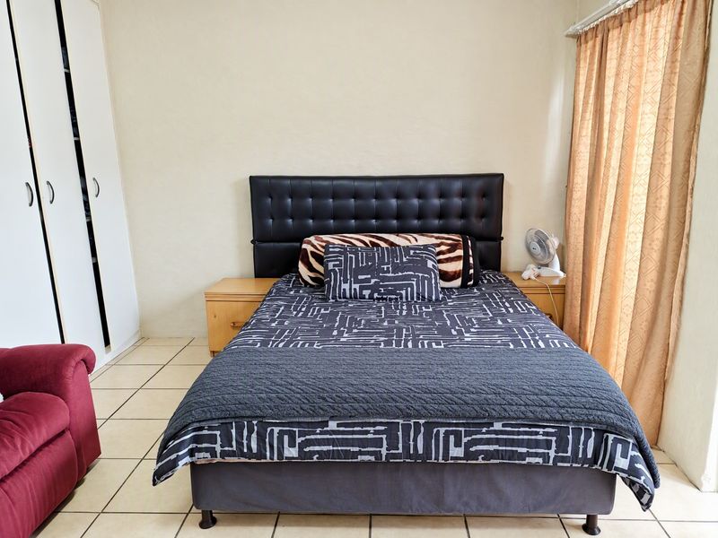 A functional bedroom featuring tiled flooring and a built-in wardrobe, providing essential storage space.