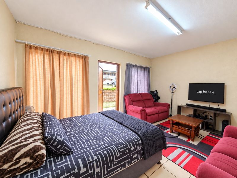 Spacious bedroom featuring tiled flooring, direct exterior access, and functional lighting, offering a versatile layout for comfortable living.