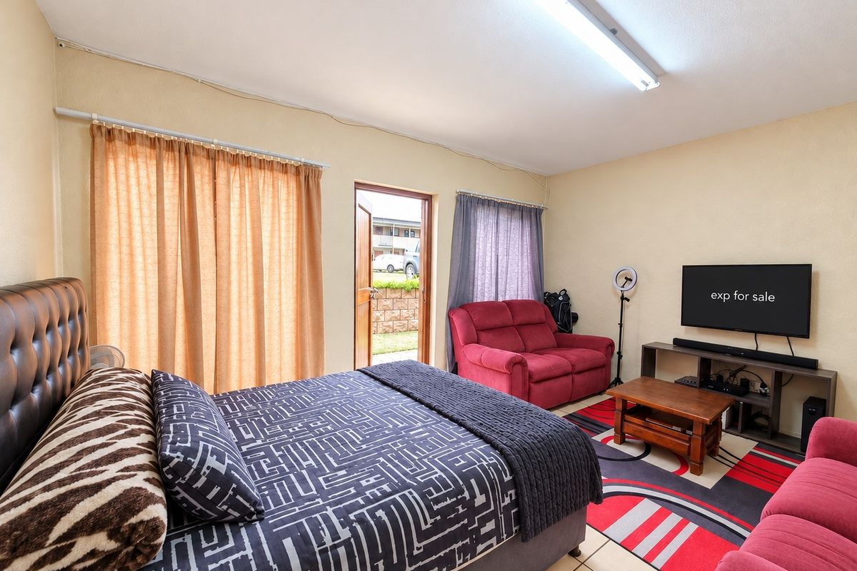 Spacious bedroom featuring tiled flooring, direct exterior access, and functional lighting, offering a versatile layout for comfortable living.
