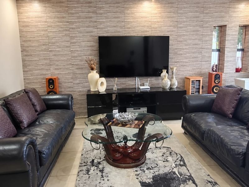 A well-maintained living room featuring a textured feature wall, tiled flooring, and recessed lighting, creating a comfortable and modern atmosphere.
