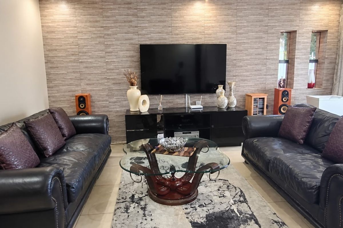 A well-maintained living room featuring a textured feature wall, tiled flooring, and recessed lighting, creating a comfortable and modern atmosphere.