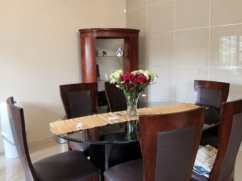 A dining area featuring neutral tiled flooring and a modern tiled feature wall, providing a clean and contemporary backdrop for meals.