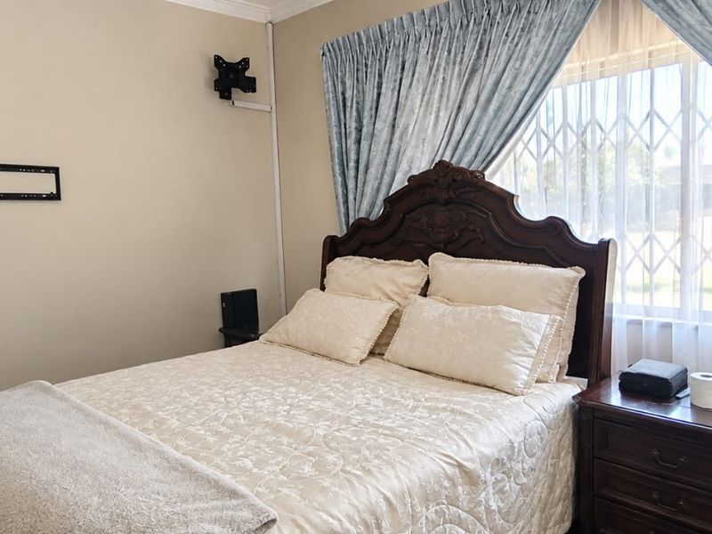 A bedroom featuring a window with a security gate and curtain rails, providing natural light and essential security features.