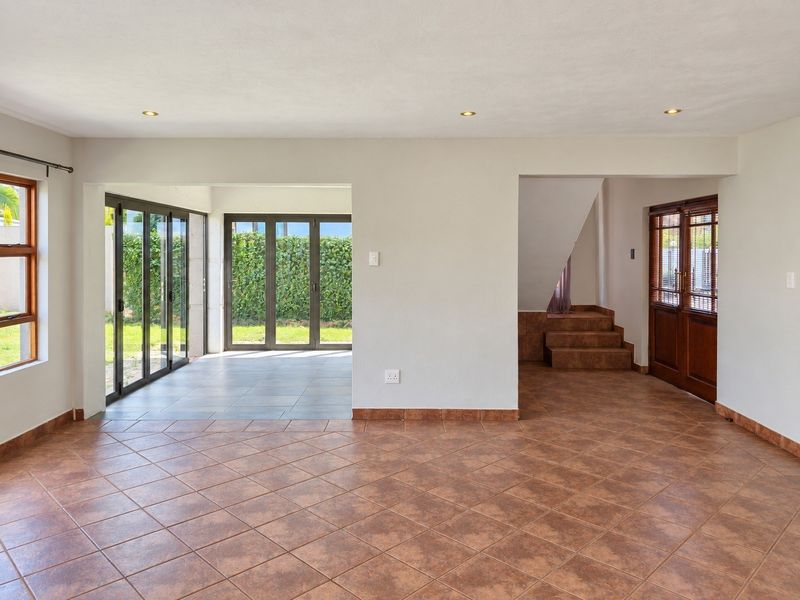 Spacious, light-filled living area featuring neutral walls, tiled flooring, and large aluminium sliding doors providing seamless access to the garden.