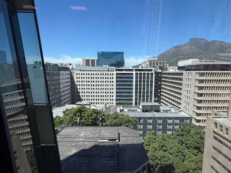 A clear elevated view of the surrounding city skyline and mountain range captured through a large office window.