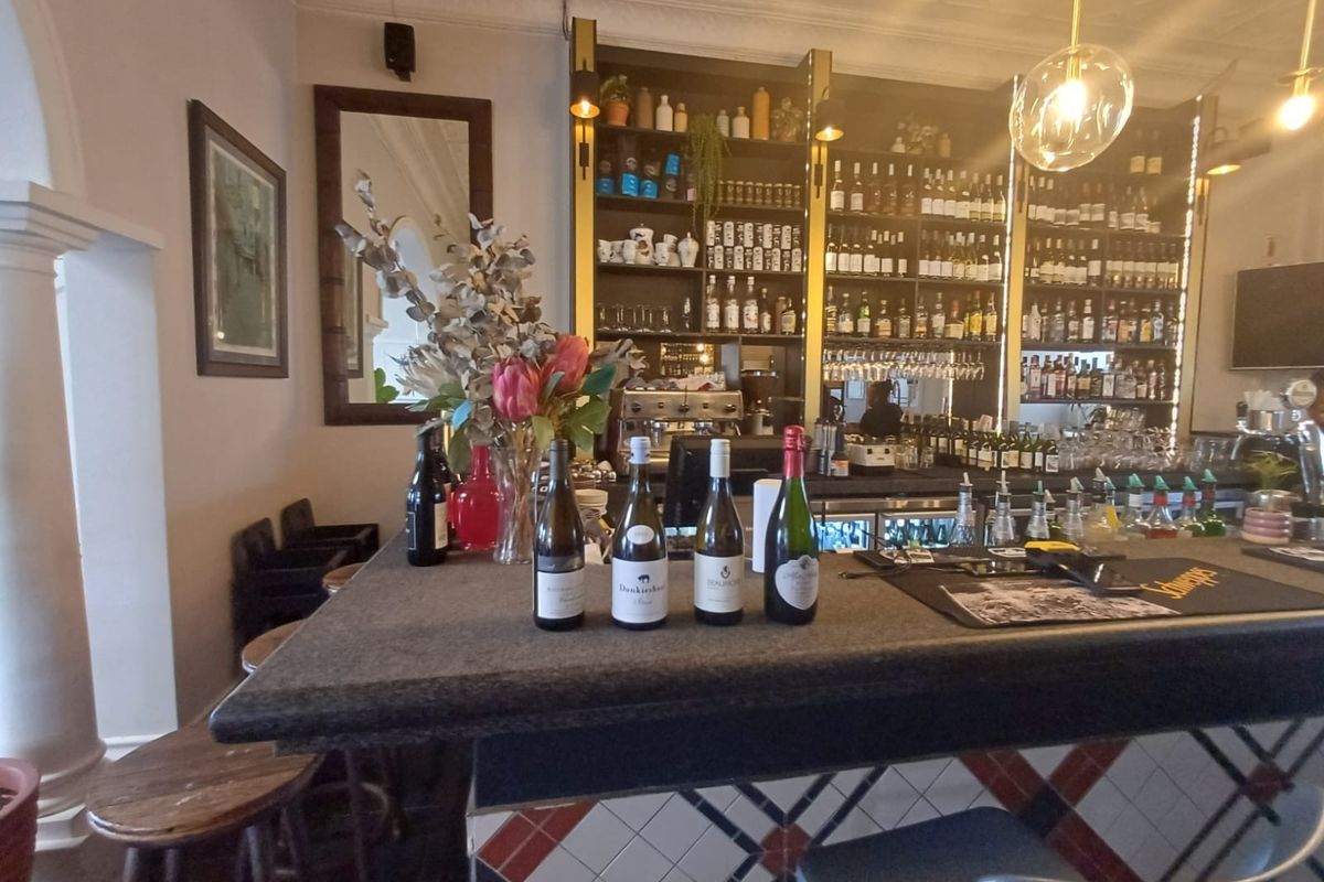 A well-appointed bar area featuring a tiled counter, extensive built-in shelving for display, and decorative ceiling cornicing.