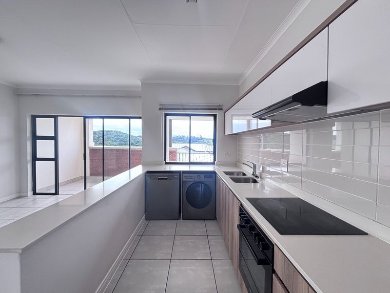 Modern kitchen featuring sleek cabinetry, stone countertops, integrated appliances, and tiled flooring, with direct access to a balcony area.