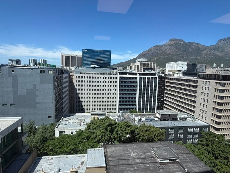 An elevated city view showcasing surrounding office buildings and a prominent mountain backdrop.