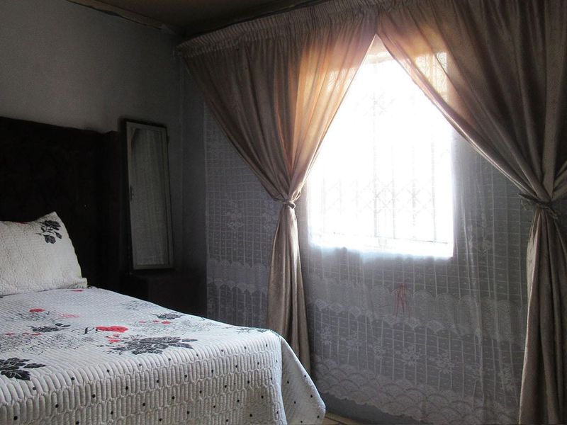 A bedroom featuring a window with a security gate and curtains.