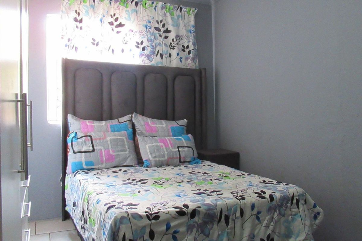 A compact bedroom featuring tiled flooring and a built-in wardrobe, providing functional storage space.
