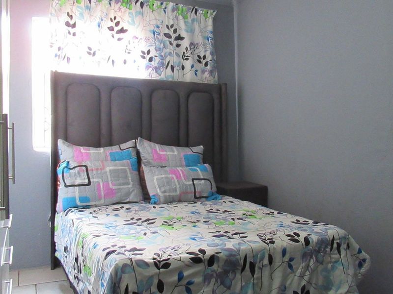 A compact bedroom featuring tiled flooring and a built-in wardrobe, providing functional storage space.
