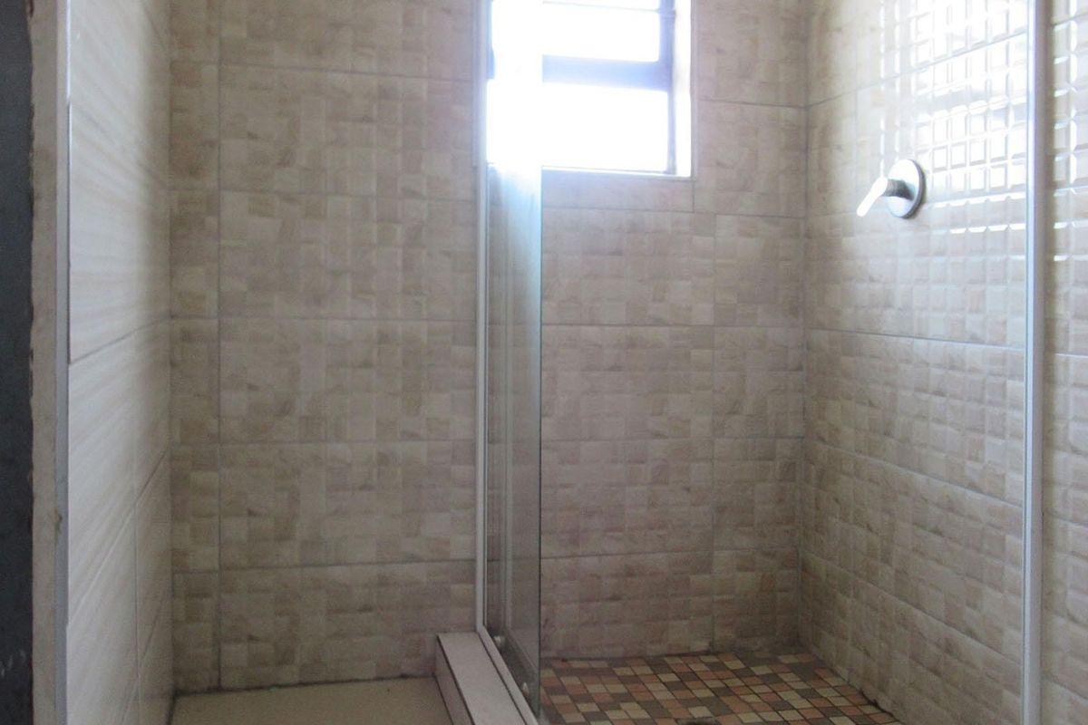A functional shower area featuring tiled walls, a glass shower enclosure, and a built-in shower mixer.
