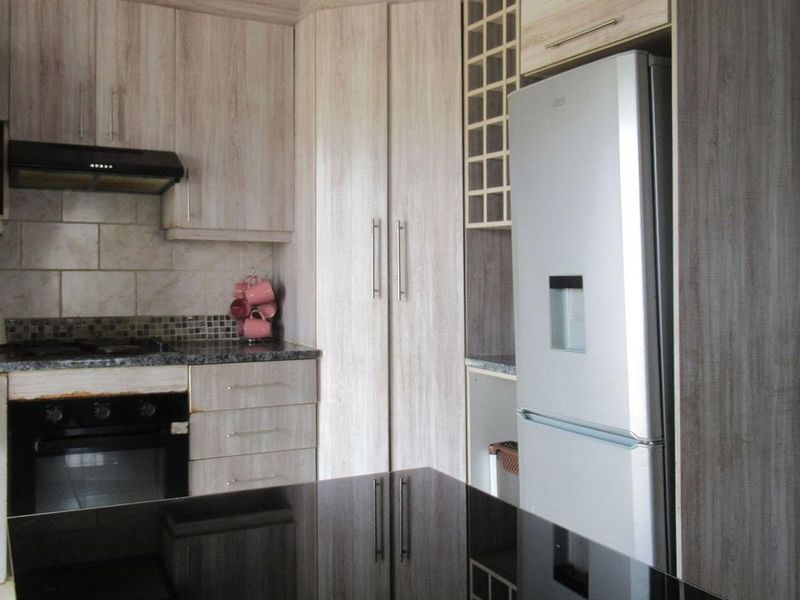 A functional kitchen featuring wood-look cabinetry, granite countertops, a built-in oven, and a tiled backsplash with integrated storage solutions.