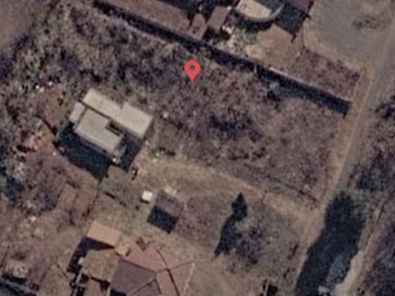 Aerial view of a vacant residential plot showing existing boundary walls and surrounding neighborhood context.