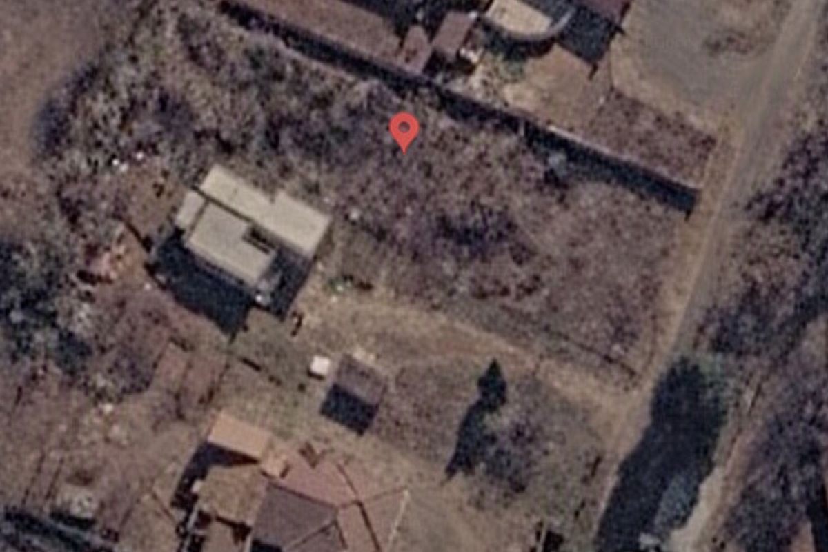 Aerial view of a vacant residential plot showing existing boundary walls and surrounding neighborhood context.