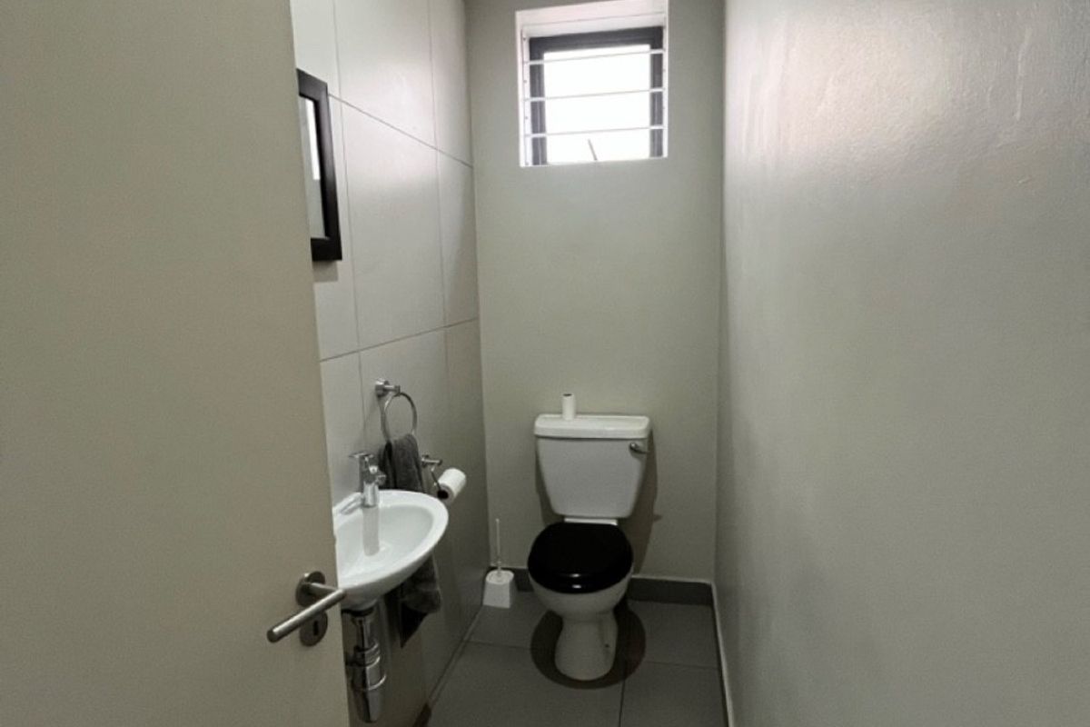 A compact guest bathroom featuring a wall-mounted basin, toilet, and neutral tiled finishes.