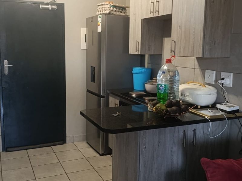 A functional kitchen featuring wood-look cabinetry, granite countertops, tiled flooring, and a built-in electric hob, providing a practical workspace.