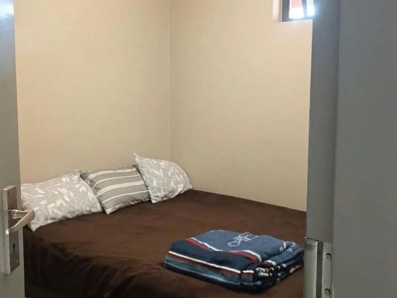 A compact bedroom featuring neutral wall finishes and a high-level window for natural light.