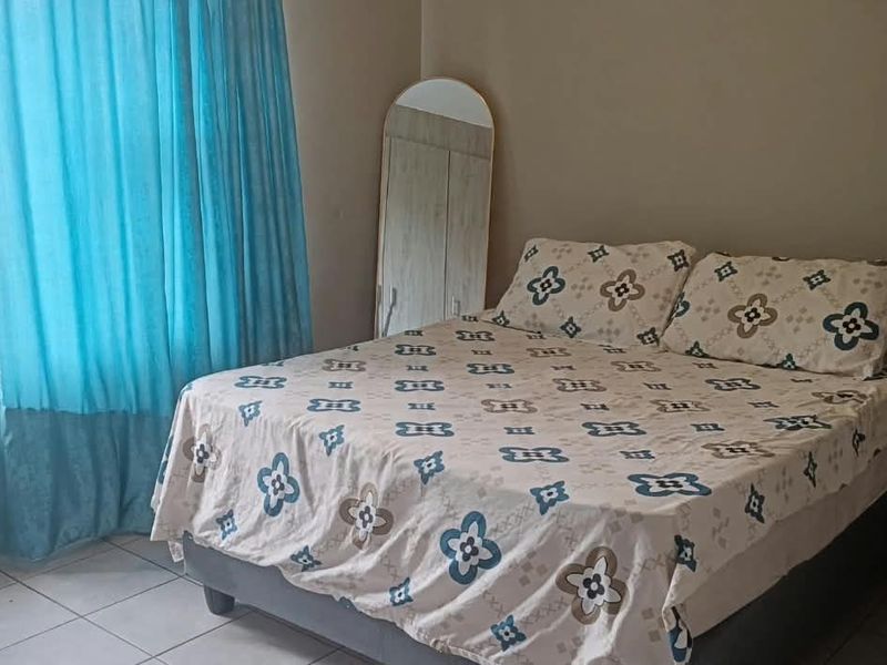 A functional bedroom featuring tiled flooring and built-in cupboards, providing essential storage space.
