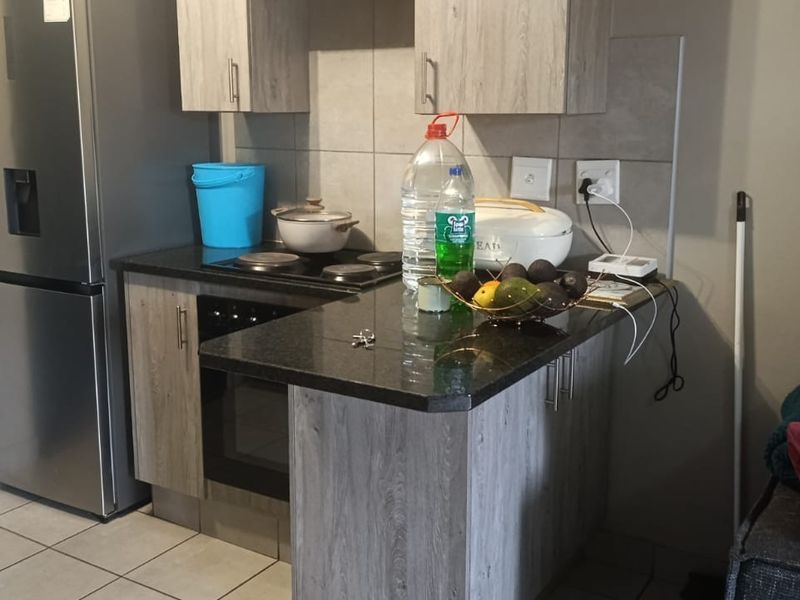 Compact kitchen featuring wood-look cabinetry, dark laminate countertops, built-in oven and hob, and tiled backsplash, providing a functional cooking space.