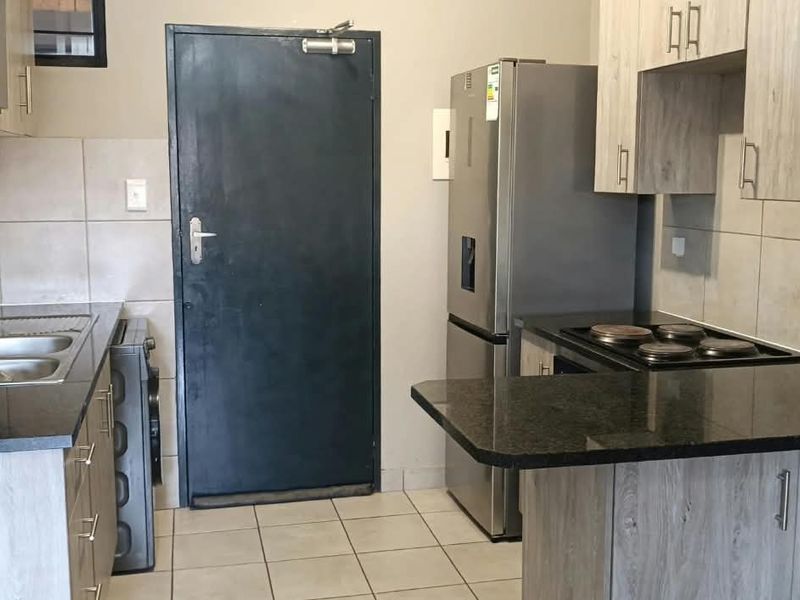 A functional kitchen featuring granite countertops, built-in cabinetry, a tiled backsplash, and an integrated electric hob.
