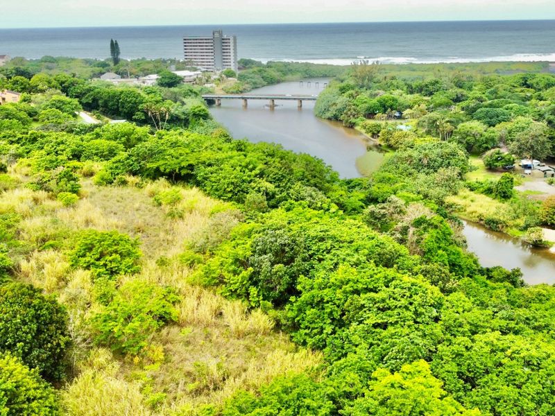An aerial view of the vacant residential land featuring lush natural vegetation, river frontage, and proximity to the coastline.