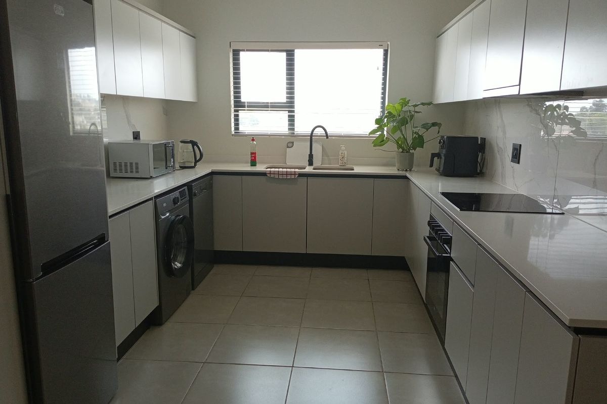 Modern kitchen featuring sleek white cabinetry, stone countertops, integrated appliances, and tiled flooring, offering a clean and functional workspace.