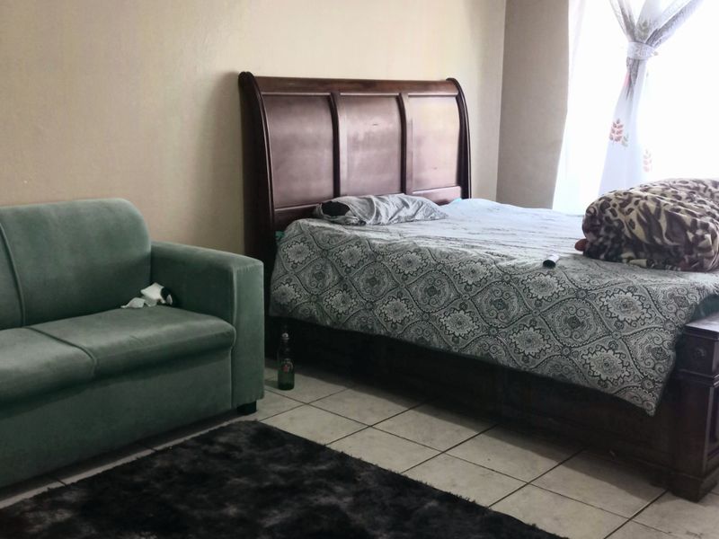 A bedroom featuring tiled flooring and natural light from a window.