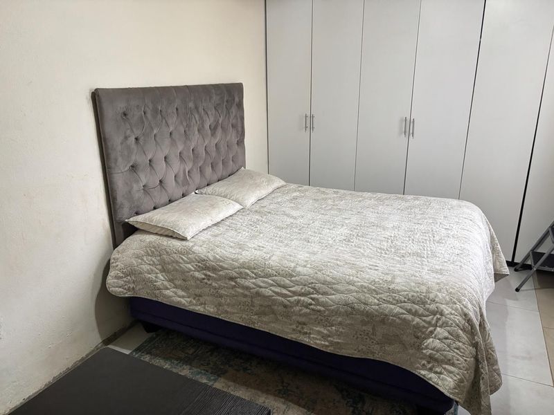 A functional bedroom featuring built-in cupboards and tiled flooring, providing a practical space with neutral finishes.