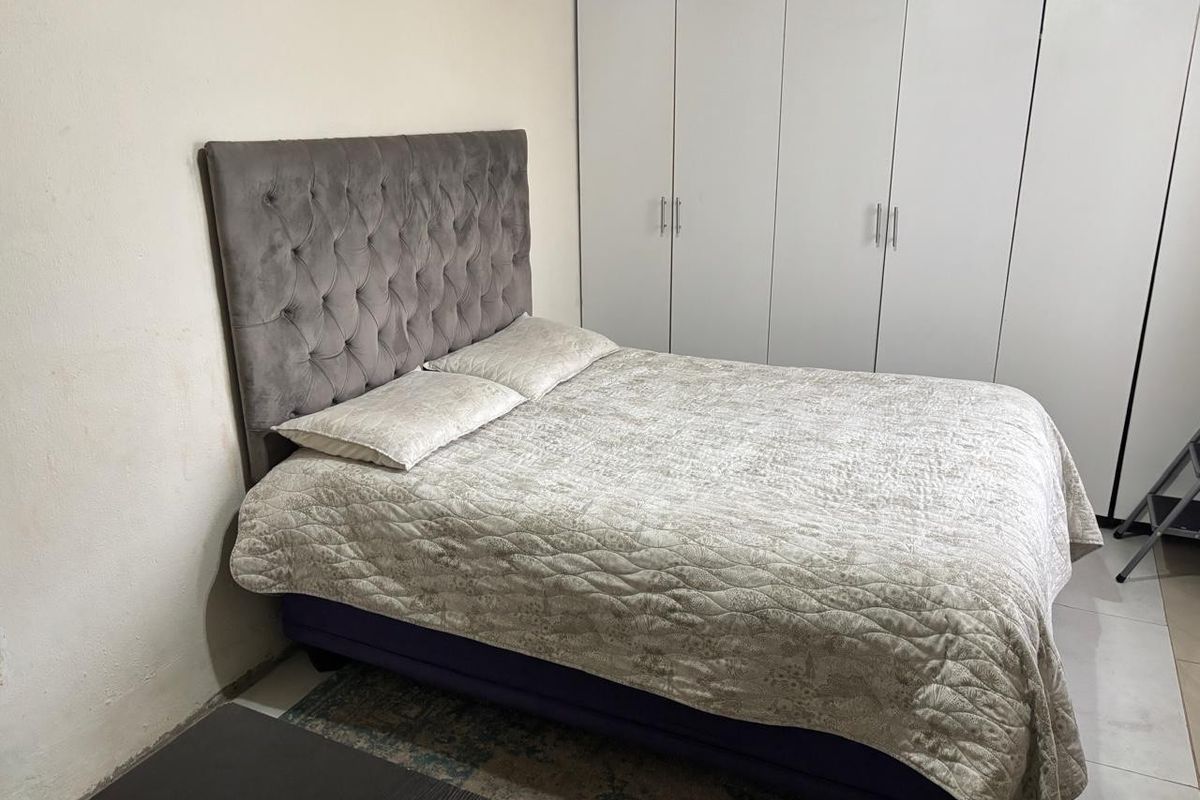 A functional bedroom featuring built-in cupboards and tiled flooring, providing a practical space with neutral finishes.