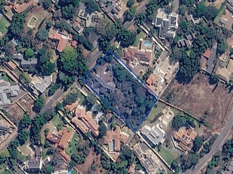 An aerial view of a residential vacant land plot surrounded by established suburban housing and mature vegetation.