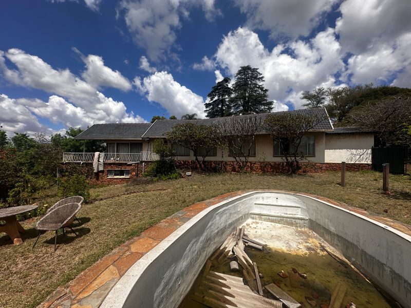 Rear view of the property featuring a residential dwelling with a balcony and a neglected swimming pool requiring significant maintenance and restoration.