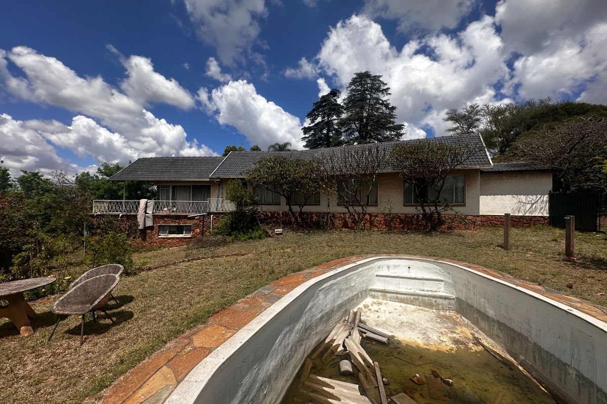 Rear view of the property featuring a residential dwelling with a balcony and a neglected swimming pool requiring significant maintenance and restoration.