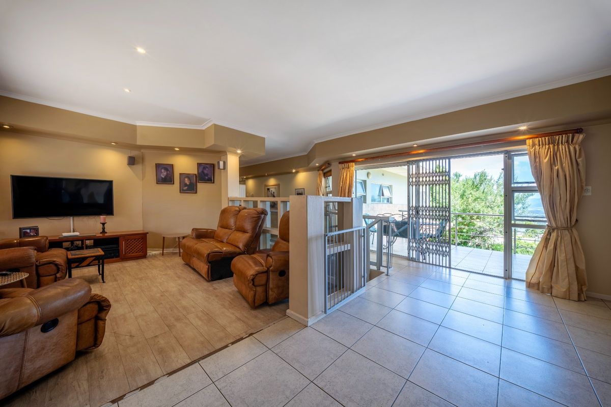 Spacious open-plan living area featuring tiled and laminate flooring, recessed lighting, and large sliding doors providing access to an outdoor balcony.