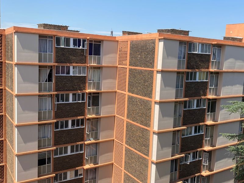 A view of the multi-story apartment building facade featuring brickwork and concrete detailing.