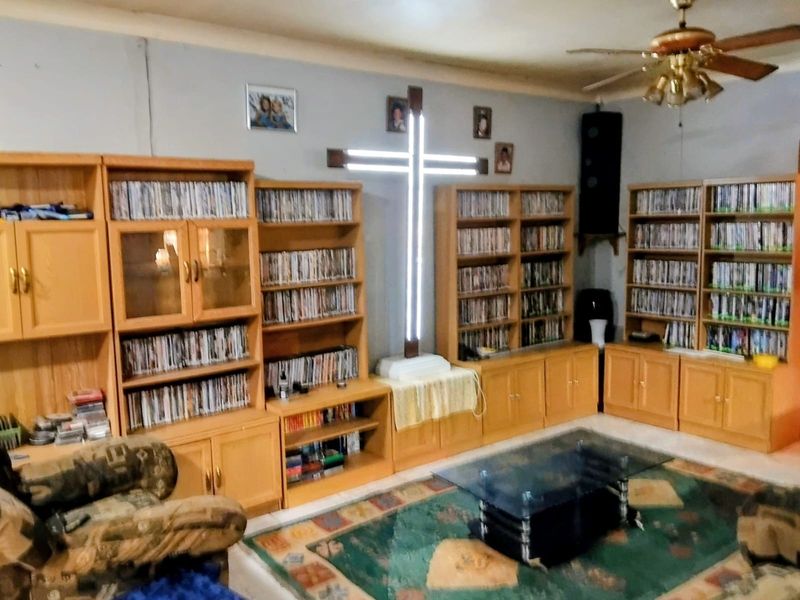 A living room featuring extensive built-in wooden cabinetry and a ceiling fan, offering significant storage potential.