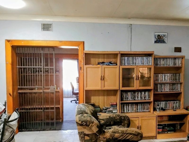 Living area featuring a security gate leading to an adjacent room and built-in wooden shelving units.