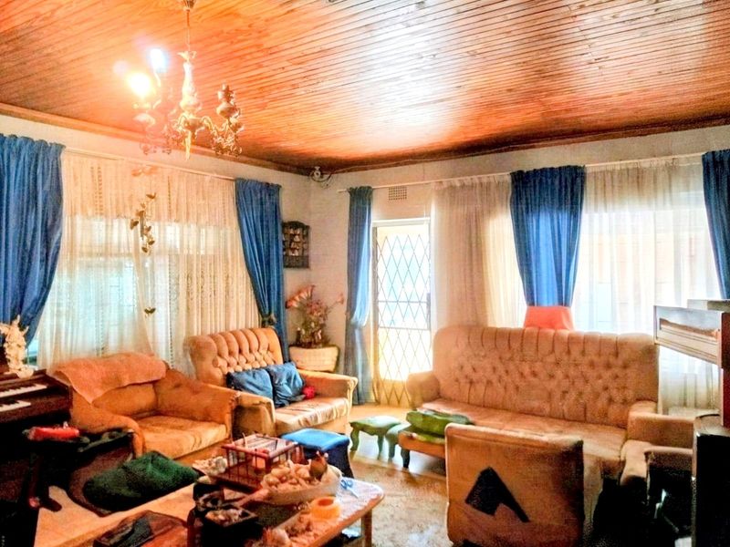A living room featuring a traditional timber tongue and groove ceiling and large windows with security gate access.