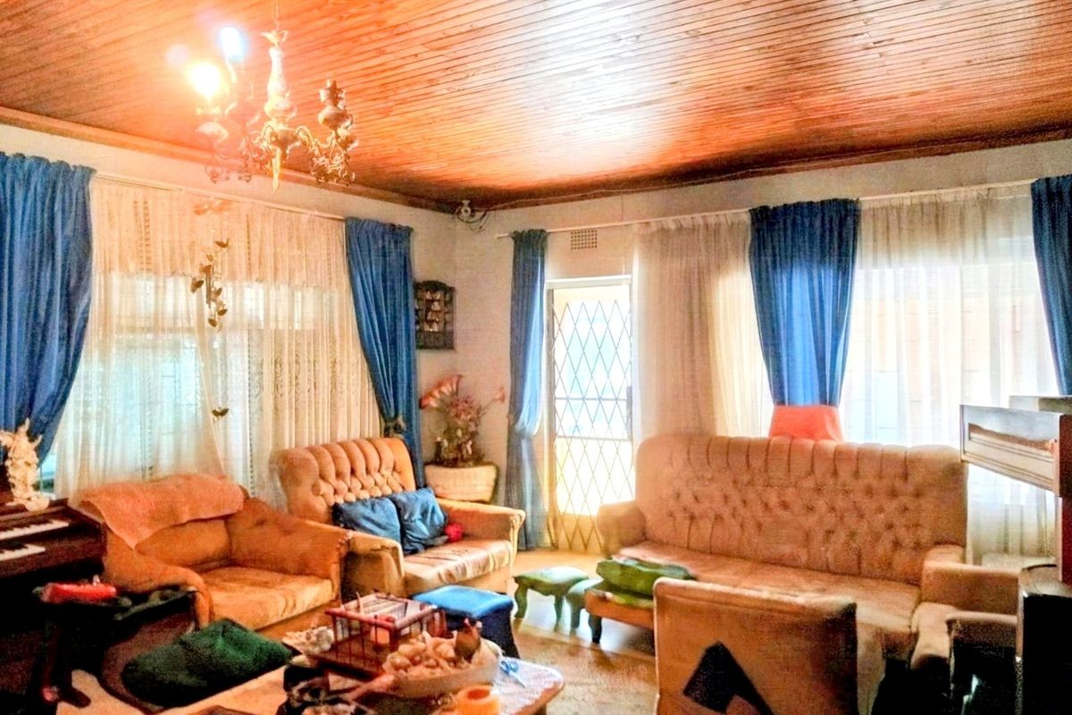 A living room featuring a traditional timber tongue and groove ceiling and large windows with security gate access.