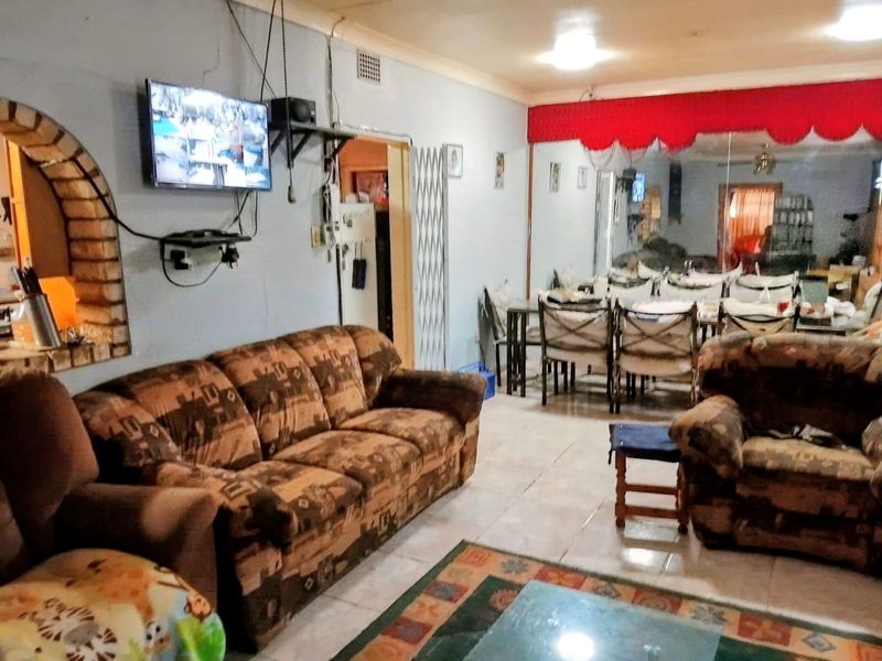 Open plan living and dining area featuring tiled flooring, a decorative brick archway, and a large mirrored wall section.
