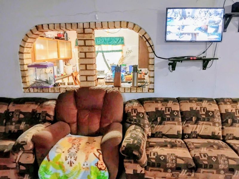 Open plan living area featuring a brick archway looking into the kitchen, with wall-mounted security monitoring equipment.